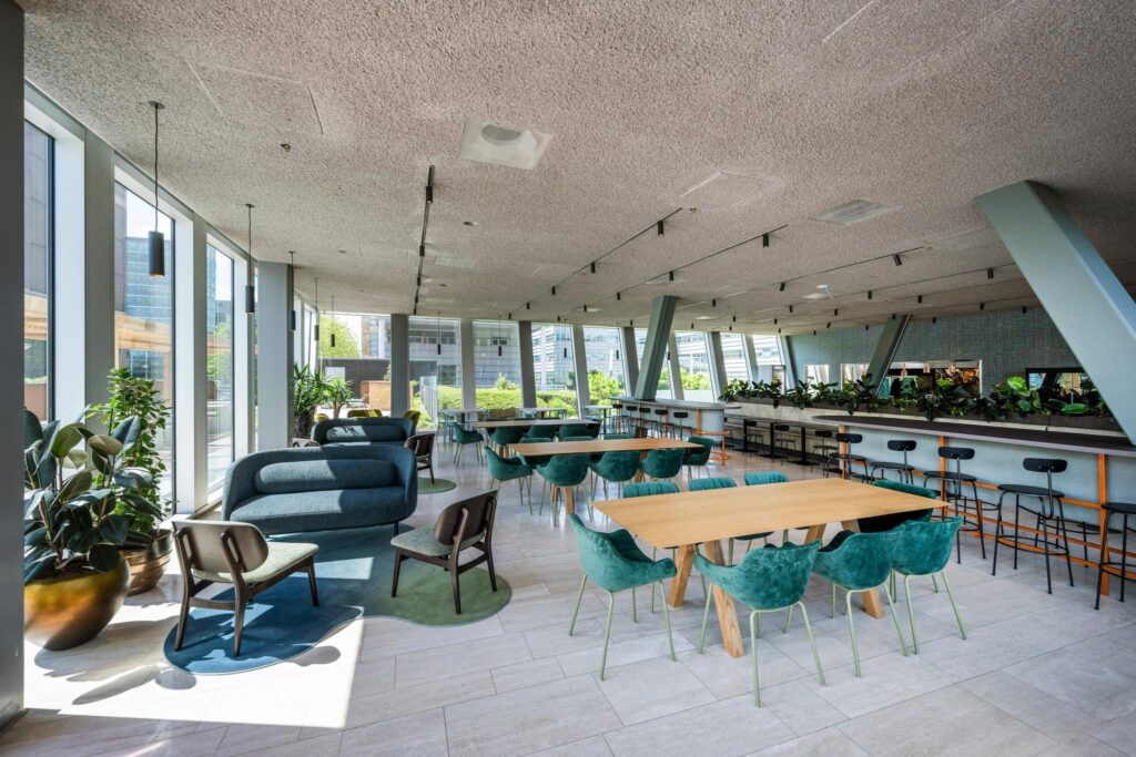 Moderne, lichtovergoten gemeenschappelijke ruimte met zithoeken, werktafels en veel groen aan de David Ricardostraat.